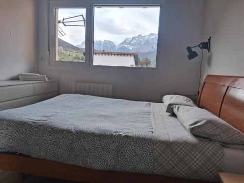 a bedroom with a bed and a window with mountains at Mirando a los Picos de Europa in Potes