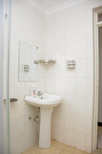 a white bathroom with a sink and a mirror at The π Homes in Eldoret