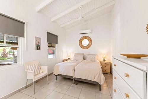 a white bedroom with a bed and a chair at Dushi Boho in Willemstad