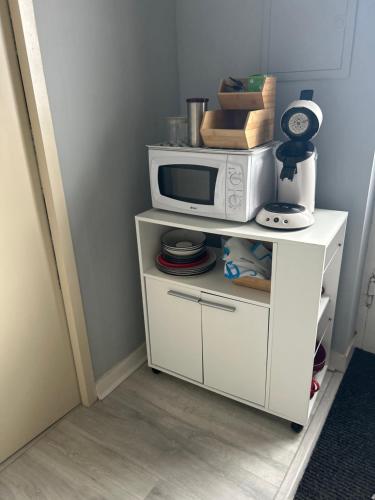 a white cabinet with a microwave on top of it at Chez Elie in Saintes