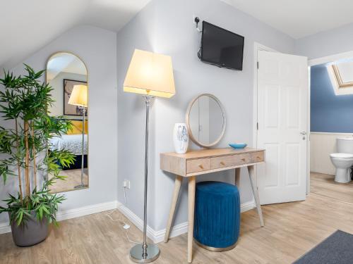 a room with a vanity and a mirror and a lamp at Pink Blossom in Clifden