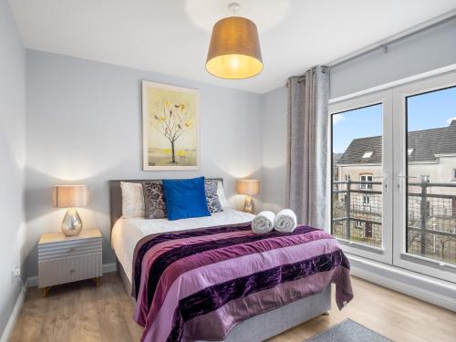 a bedroom with a bed and a large window at Pink Blossom in Clifden