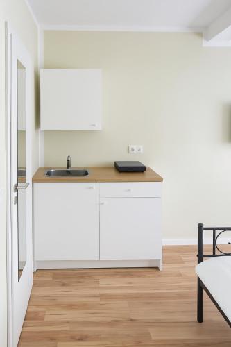 a kitchen with white cabinets and a sink at My Loft in Hagen