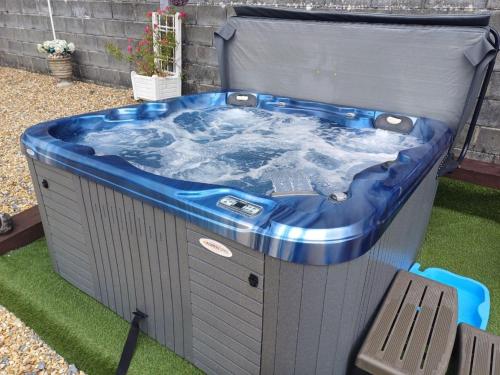 a jacuzzi tub in a yard with a chair at Sunny Bank - bungalow with hot tub and extra accessibility in Carmarthen