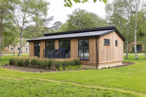a wooden cabin with a black roof on a grass field at Blenheim Palace Lodge Retreat in Woodstock