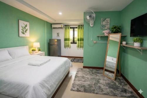 a bedroom with a white bed and a green wall at Similan Mondo Resort & Camping in Phang-nga