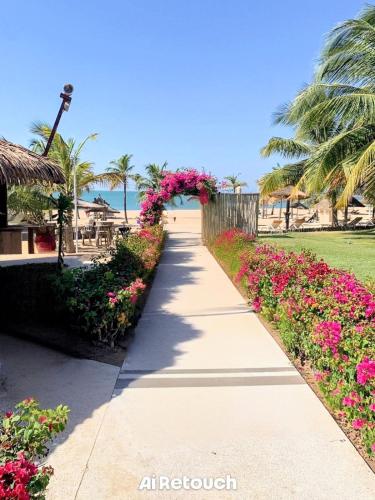 ein Strandweg mit Blumen und Palmen in der Unterkunft Casa Serena Saly in Saly Portudal
