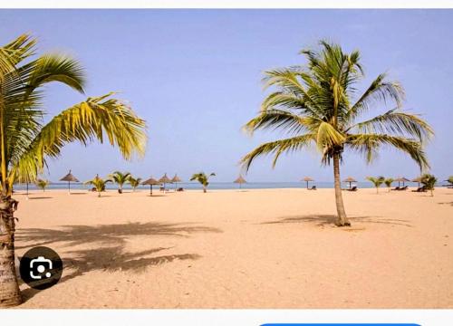 zwei Palmen mit Sonnenschirmen an einem Sandstrand in der Unterkunft Casa Serena Saly in Saly Portudal