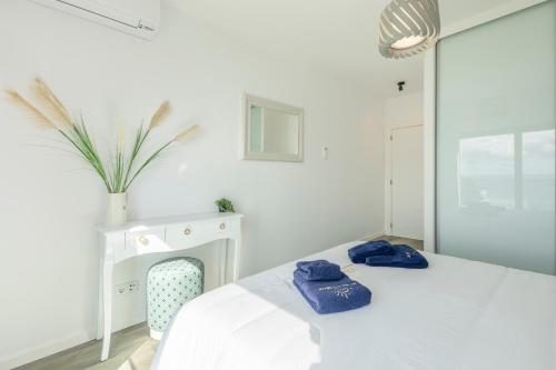 a white bedroom with two blue towels on a bed at Alma do mar luxury - Ocean front in Gaula
