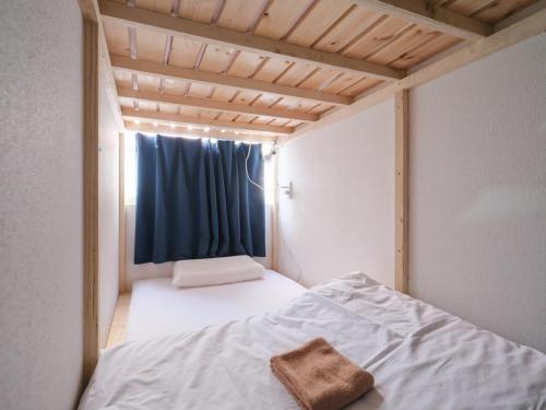 a small bedroom with a bed with a blue curtain at Akabane Dormitory-Men Only in Tokyo