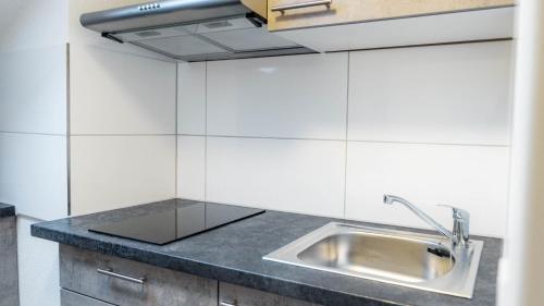 eine Küche mit Edelstahlspüle und weißen Wänden in der Unterkunft E&B Hotel Korb bei Waiblingen & Stuttgart in Korb