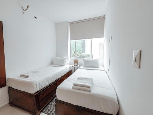 two beds in a room with a window at Fee4Me Flat near Neomundo in Bucaramanga