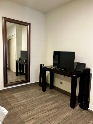 a room with a desk with a television and a mirror at LÁZARO D primer piso in Monterrey