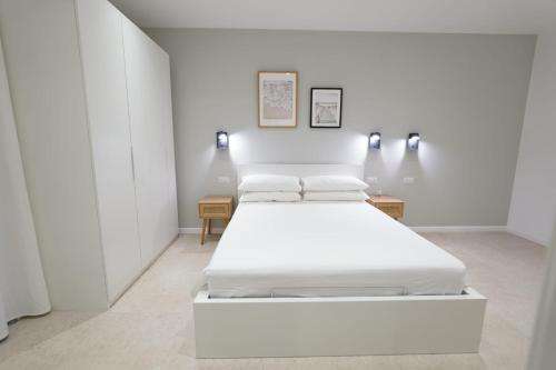 a white bedroom with a bed and two tables at ResidenzaMarèa in Scalea