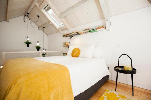 a bedroom with a large white bed with a yellow blanket at GET a Cactus and Books studio in Porto