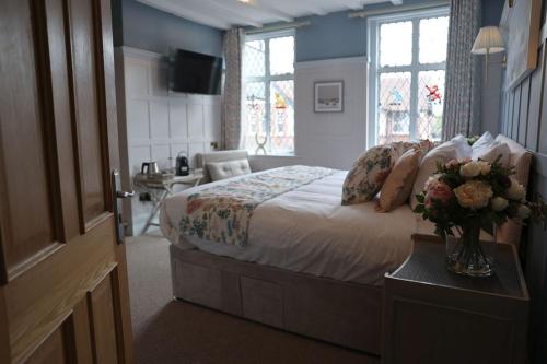 a bedroom with a bed with a vase of flowers on a table at The Hart in Uttoxeter