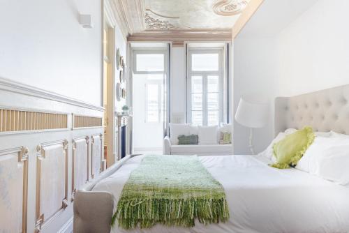 a bedroom with a large white bed with a green blanket on it at Get a Unique and Luxury Flat in Porto