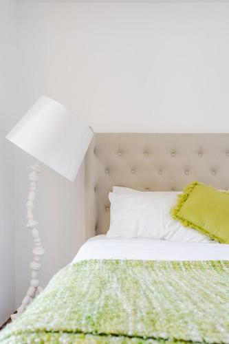 a white bed with a green blanket and a white lamp at Get a Unique and Luxury Flat in Porto