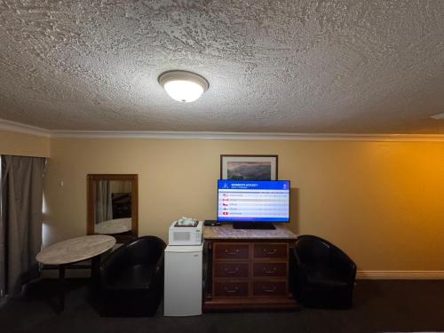 a room with a computer on a desk with chairs at Island Travel Inn in Victoria