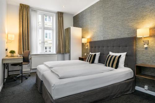 ein Hotelzimmer mit einem großen Bett und einem Schreibtisch in der Unterkunft Hotel Tiffany in Kopenhagen