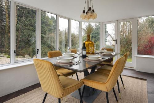a dining room with a table and chairs and windows at Bellfoot Rural Retreat and Hot Tub in Grasmere