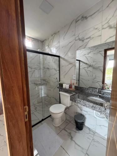 a marble bathroom with a toilet and a sink at Pousada Buganvília in Tianguá