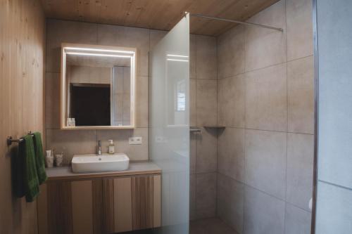 a bathroom with a sink and a shower with a mirror at Ferienwohnung Flatz in Egg