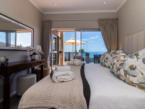 a bedroom with a bed with a desk and a mirror at Waves & Whales in Brenton-on-Sea
