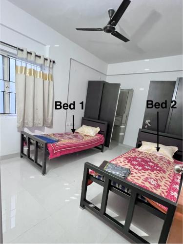 a room with two beds and a ceiling fan at shankara stays in Bangalore