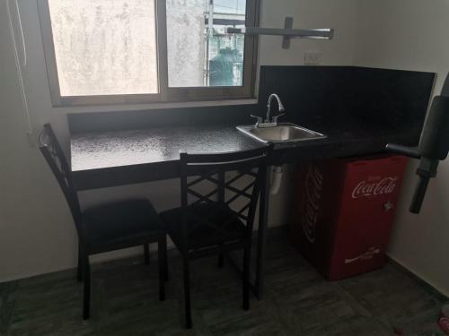 a kitchen with a counter and a sink and chairs at Gran Plaza, Cancún in Cancún