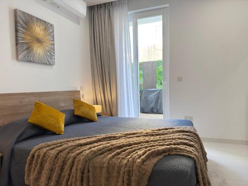 a bedroom with a bed with yellow pillows and a window at Spielberg - Garage, Outdoor Area, Close to Beach in Marsaskala