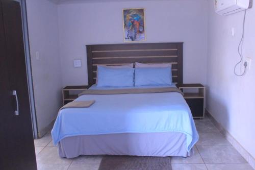 a bedroom with a large bed with blue sheets and pillows at Exodus Guesthouse Mahlakwena Stee'lpoort in Steelpoort