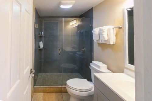 a bathroom with a toilet and a glass shower at Kona Reef Resort by Latour Group in Kailua-Kona