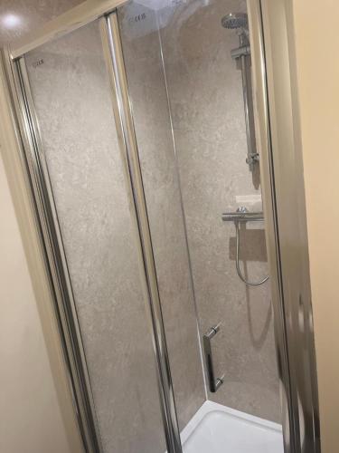 a shower with a glass door in a bathroom at Crowtrees Barns in Waterhouses
