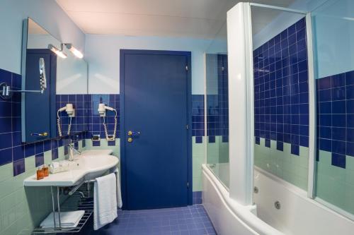 a blue bathroom with a sink and a tub at Hotel & Loisir Le Ruote in Roveleto