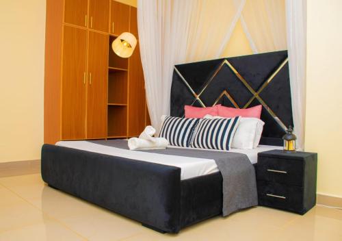 a large bed with a black headboard and pink pillows at Nook Cabins in Ruringʼu