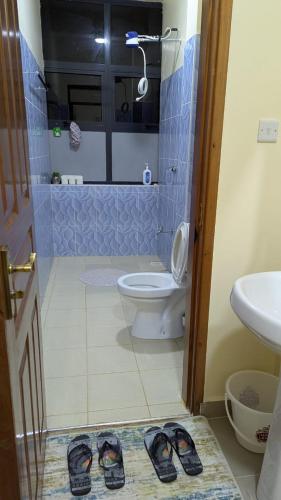a bathroom with a toilet and a pair of shoes at Nook Cabins in Ruringʼu