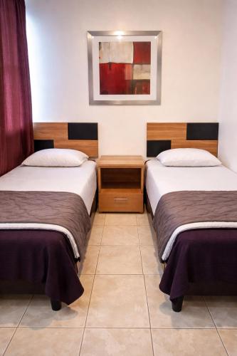 a room with two beds and a picture on the wall at Depa Centrico en Monterrey in Monterrey