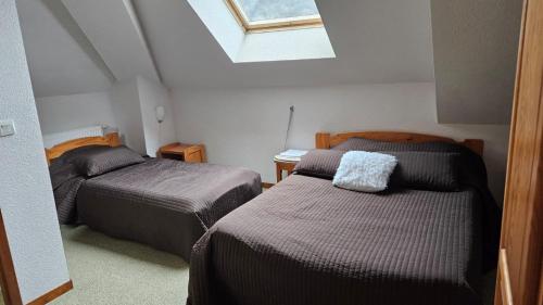 two beds in a small room with a skylight at Auberge La Cure in Oz
