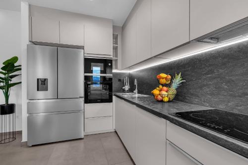 a kitchen with white appliances and a bowl of fruit on the counter at Villa Ante - Private Pool, Wellness & Gym in Šestanovac
