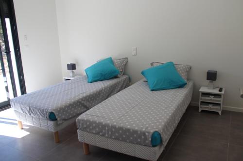 two beds with blue pillows in a room at Villa Terre des Maures in Vidauban