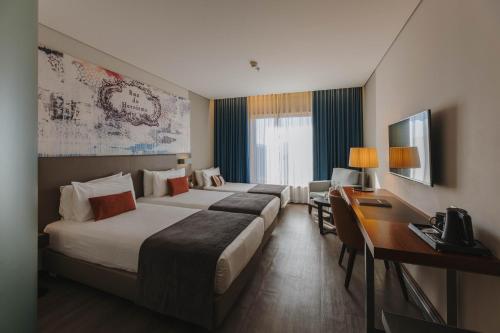 a hotel room with two beds and a desk at Timbre Heroismo in Porto