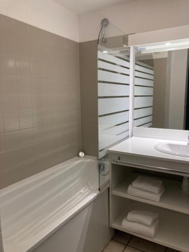 a bathroom with a sink and a tub and a mirror at Comfort Aparthotel Divonne La Versoix in Divonne-les-Bains