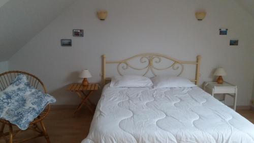 a bedroom with a white bed and two chairs at le Questel in Plouézec
