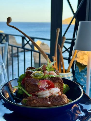 a plate of food on a table near the ocean at Hotel Mezzatorre in Ventotene