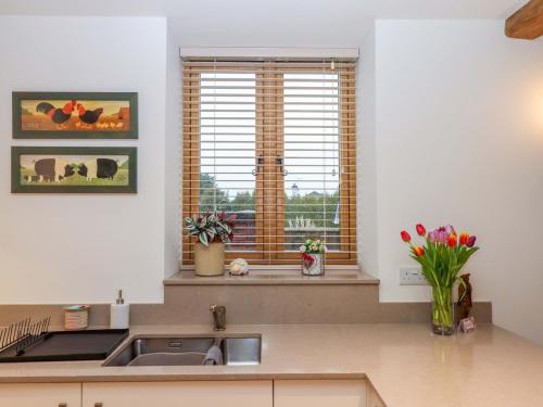 a kitchen with a sink and a window with tulips at Grange Cottage in Crediton