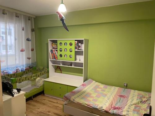 a green bedroom with a bed and a book shelf at Luxurious flat - Pleven center in Pleven