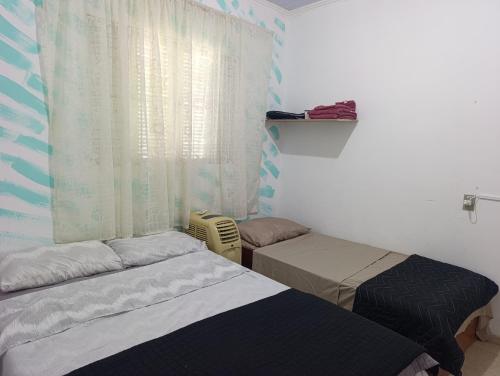a bedroom with two twin beds and a window at Kit 400mts da praia in Bertioga