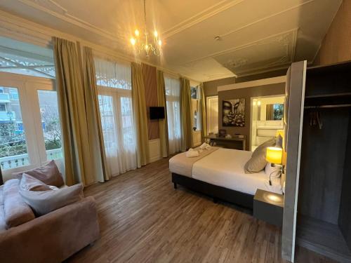 a large bedroom with a bed and a couch at Hotel Andante aan Zee in Scheveningen