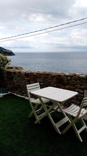 a picnic table and two chairs sitting next to the ocean at la terrazza relax in Corniglia